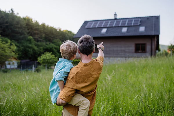 Vater mit Sohn vor Haus mit Solaranlage | Neubau Würzburg
